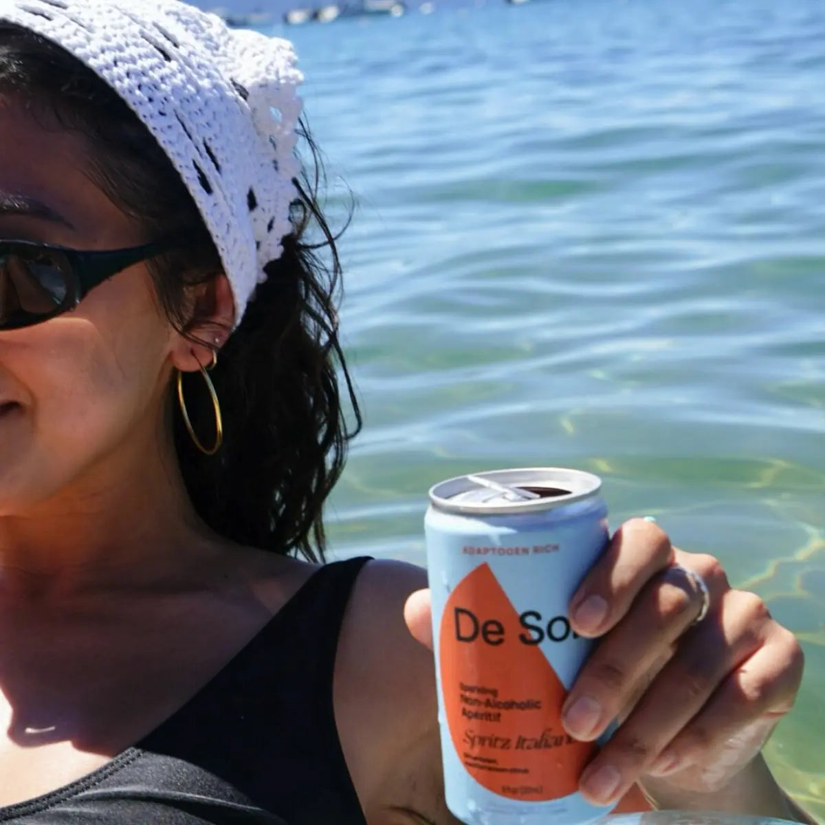 Person by the water holding a De Soi Spritz Italiano non-alcoholic aperitif can.
