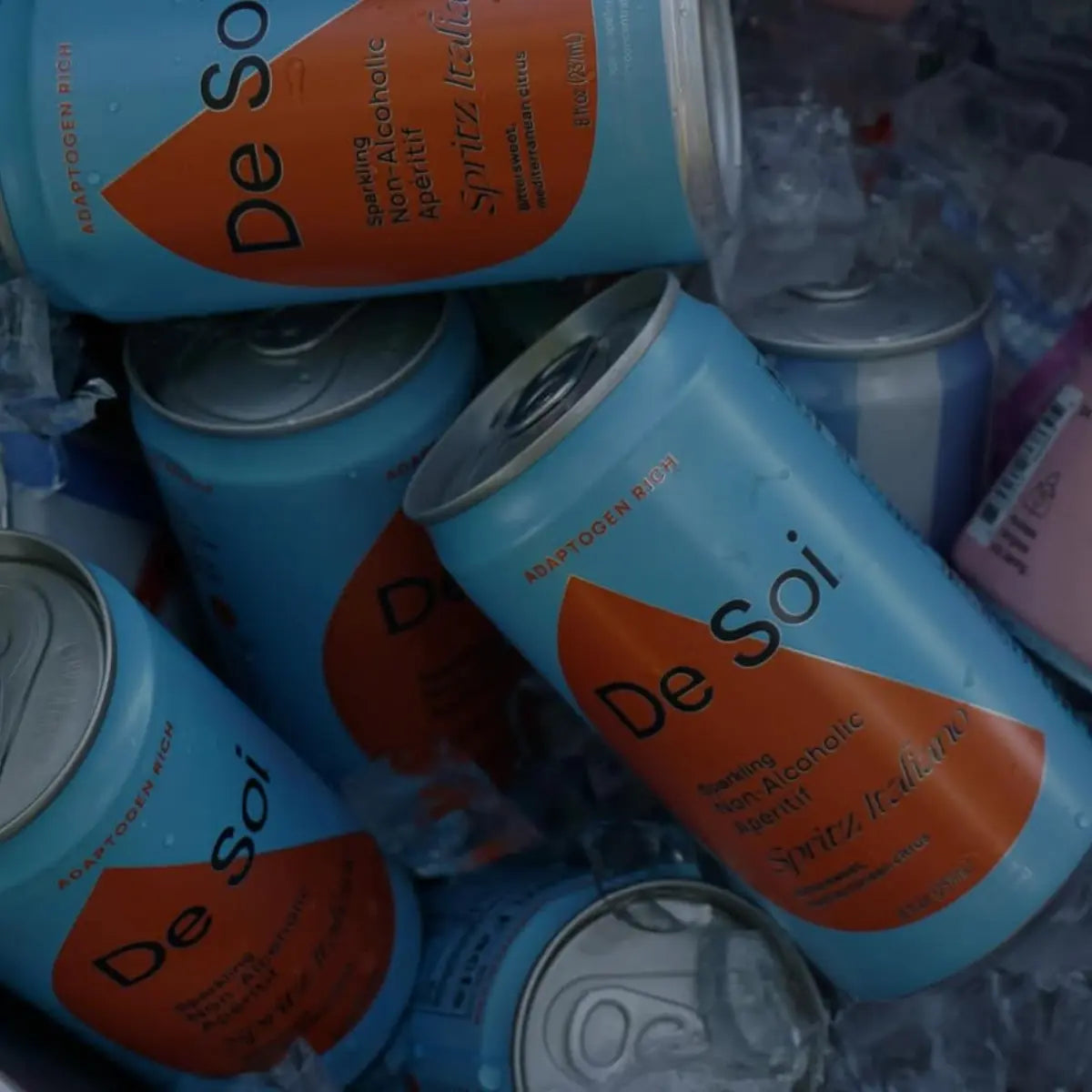 Non-alcoholic aperitif De Soi Spritz Italiano cans chilled in ice showcasing vibrant blue packaging.