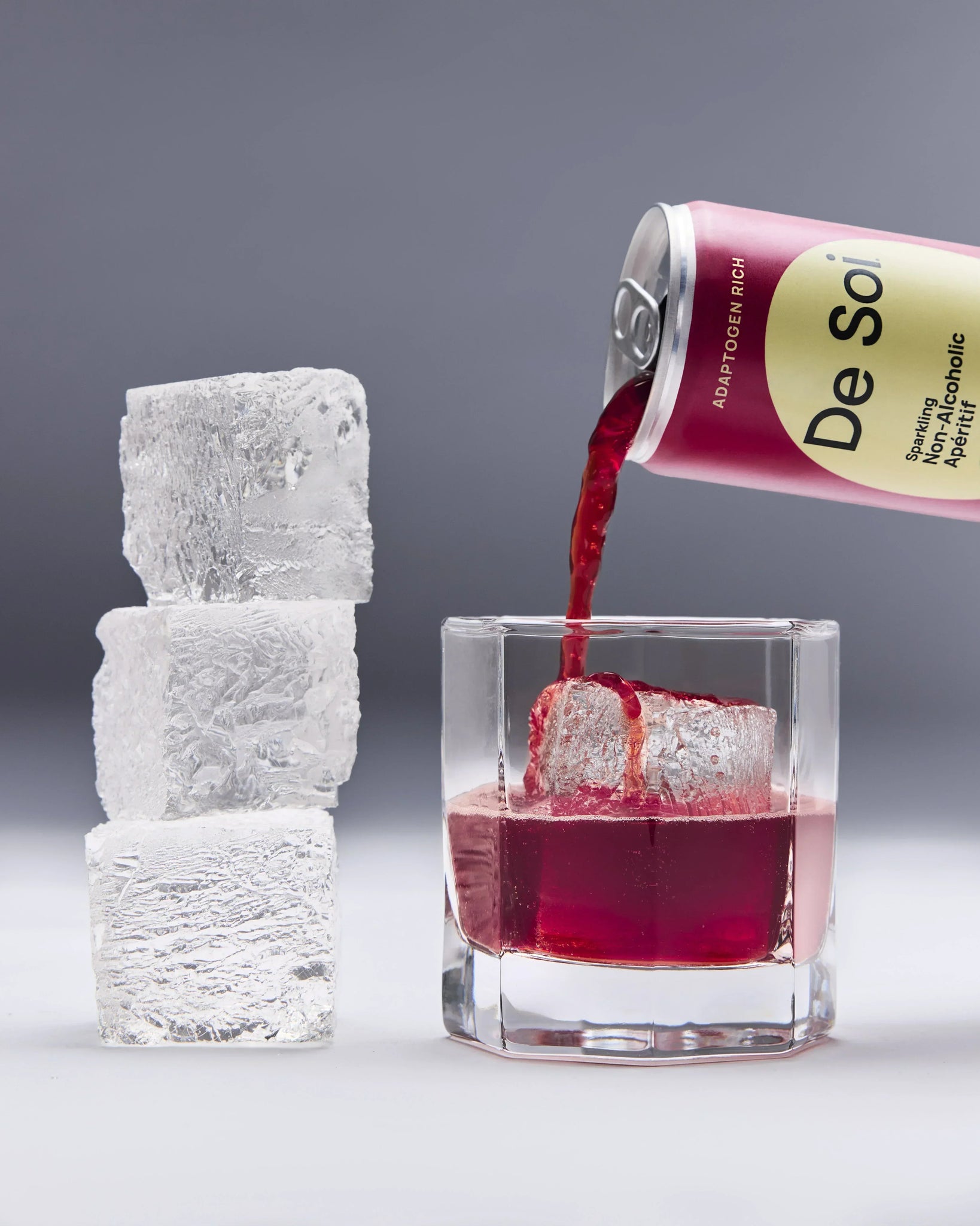 Non-alcoholic aperitif from De Soi being poured into a glass over ice cubes with a sleek backdrop