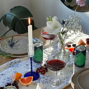 Non-alcoholic evening drinks "De Soi" on a decorated table with flowers, fruits, and a lit candle.