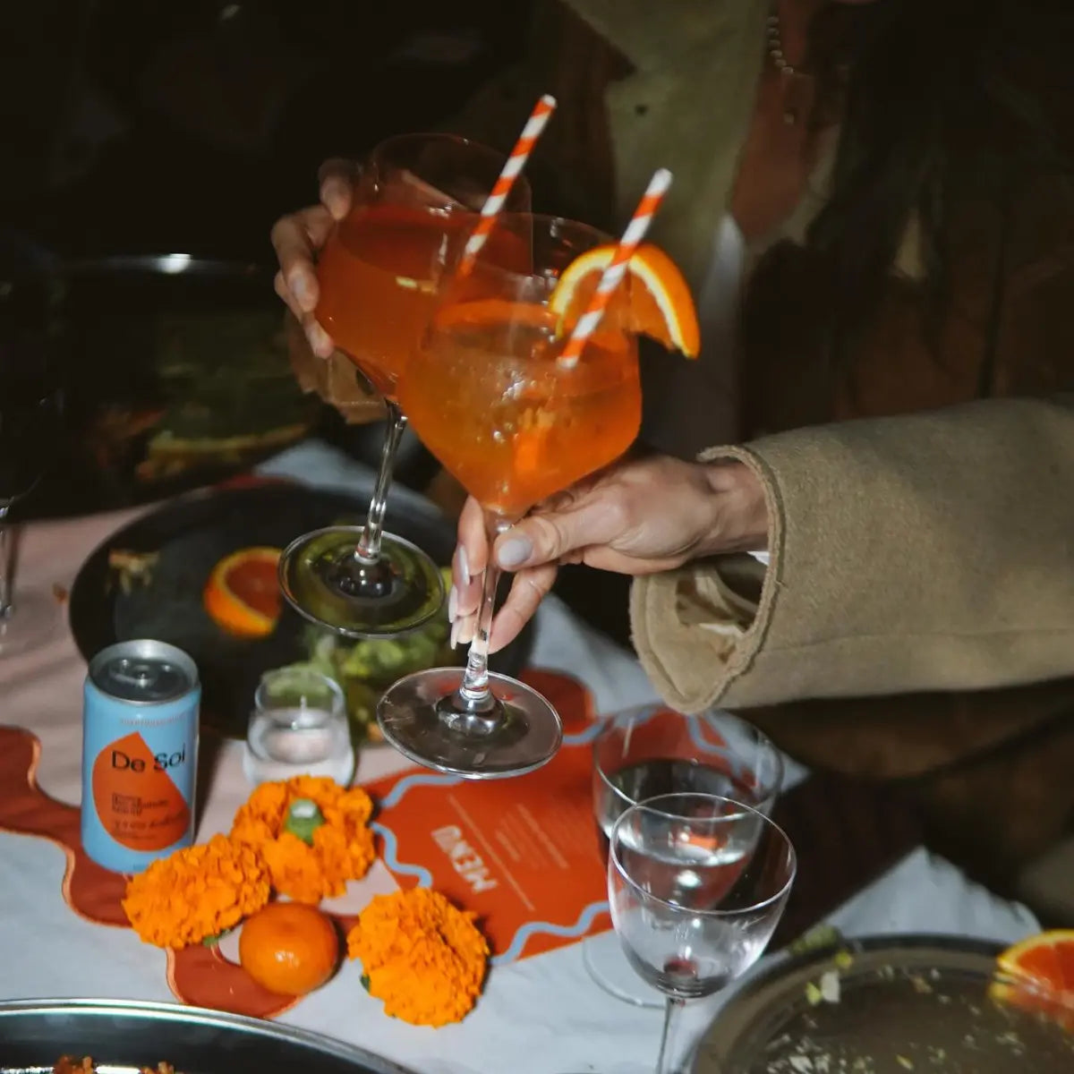 Adaptogen mocktails with citrus garnish served at a festive table alongside a can of De Soi non-alcoholic aperitif.