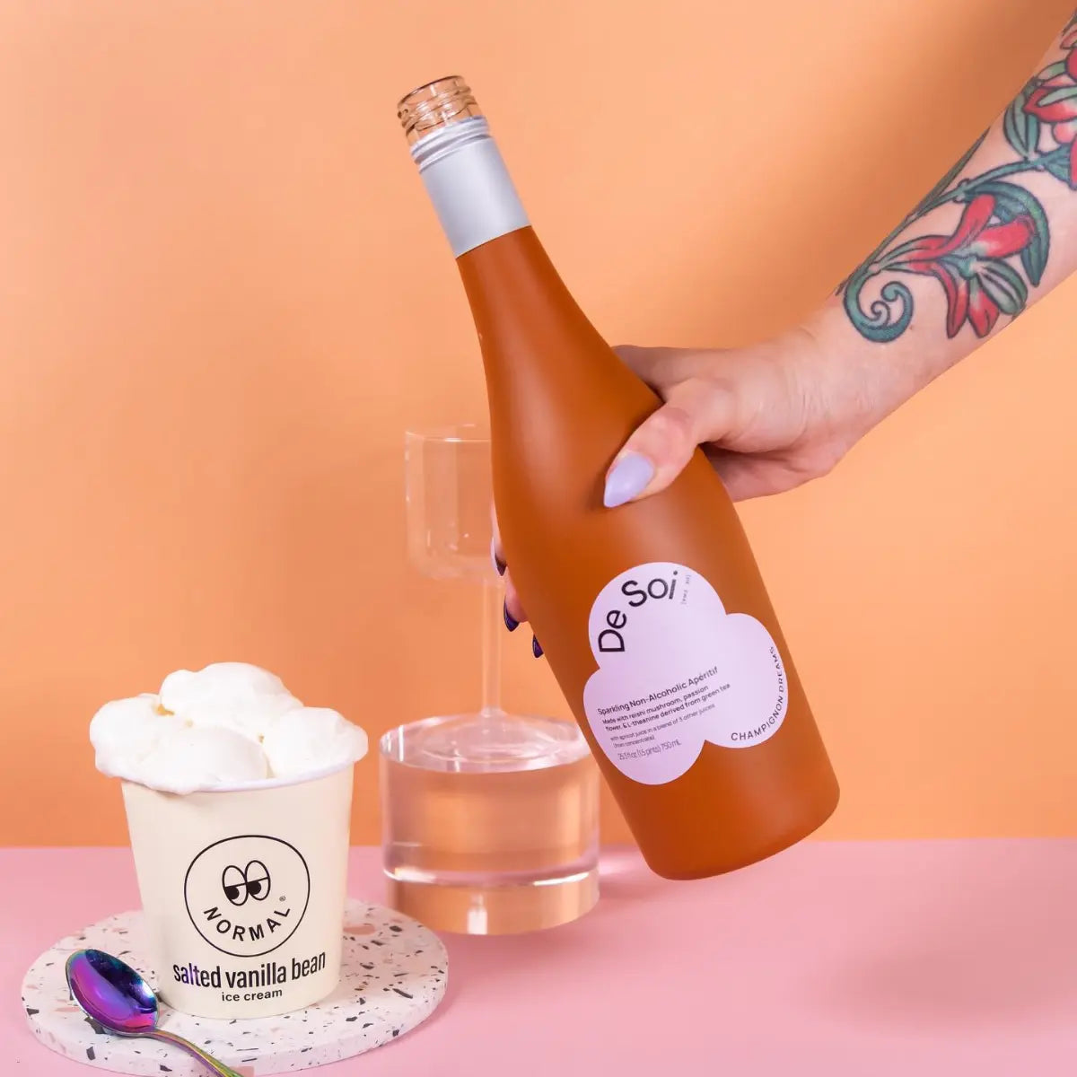Mocktail apéritif drink in a De Soi bottle paired with salted vanilla bean ice cream on a pastel background.