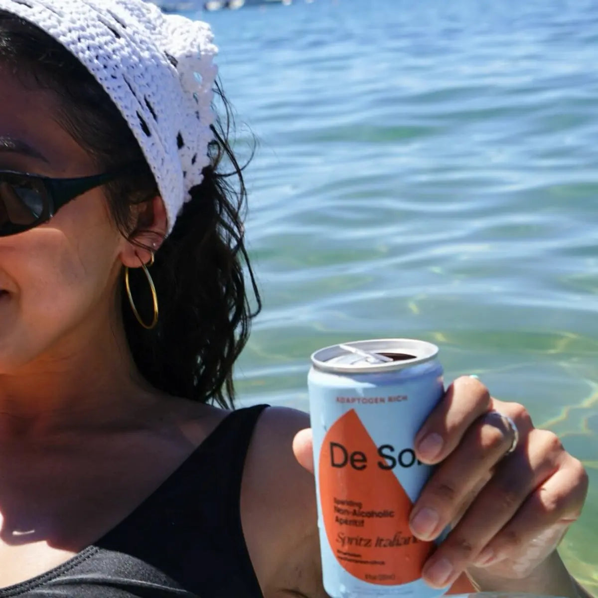 Mocktail with adaptogens held by a woman relaxing in the water on a sunny day