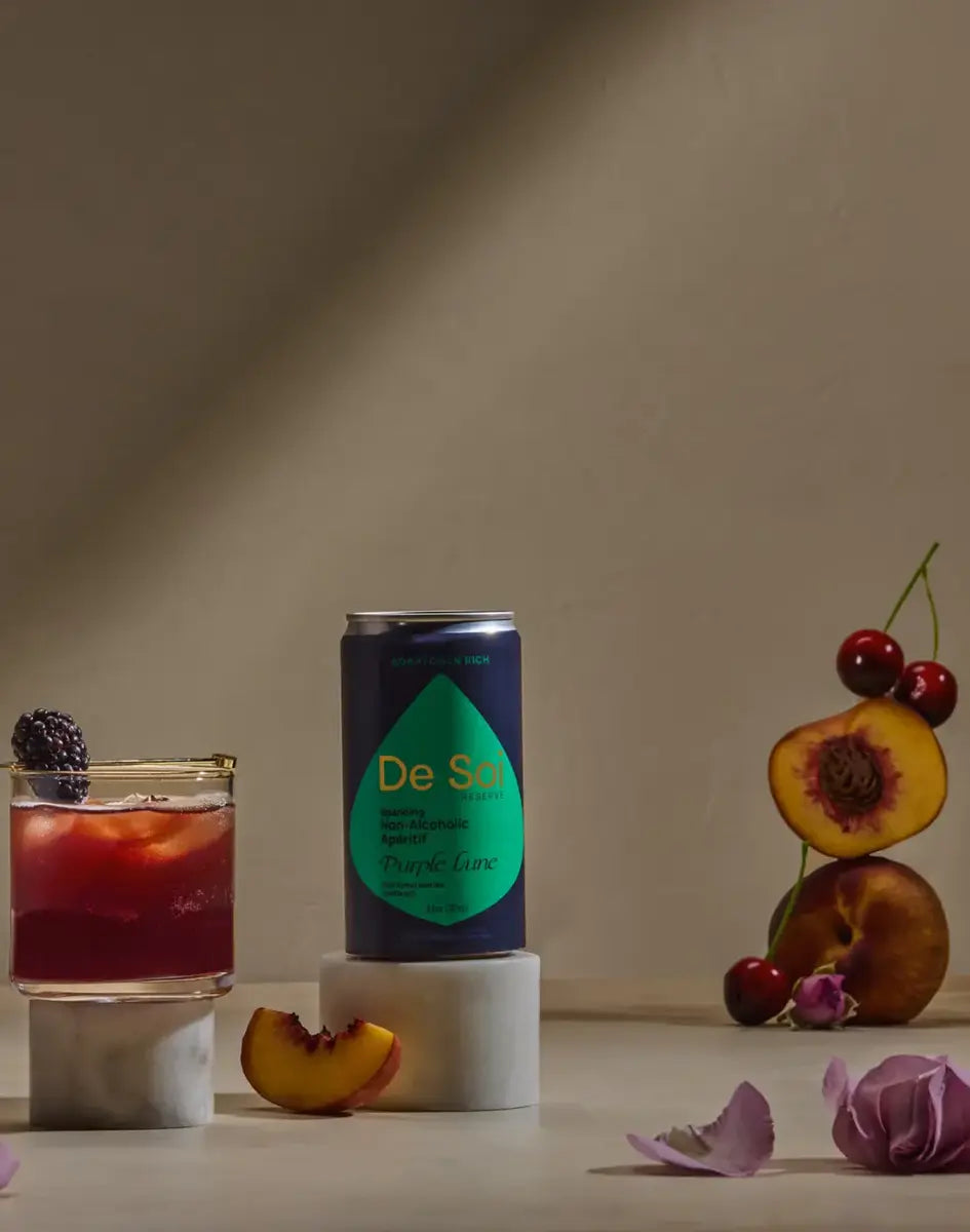 Non-alcoholic drink with De Soi Purple Lune apéritif, styled with cherries, peaches, and blackberries.