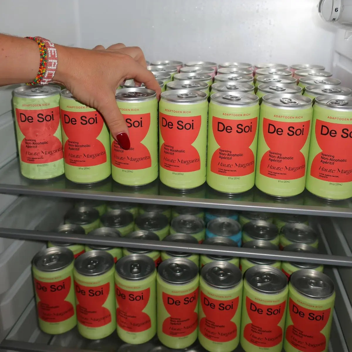 Non-alcoholic drinks arranged in a refrigerator with rows of chilled De Soi sparkling cans.