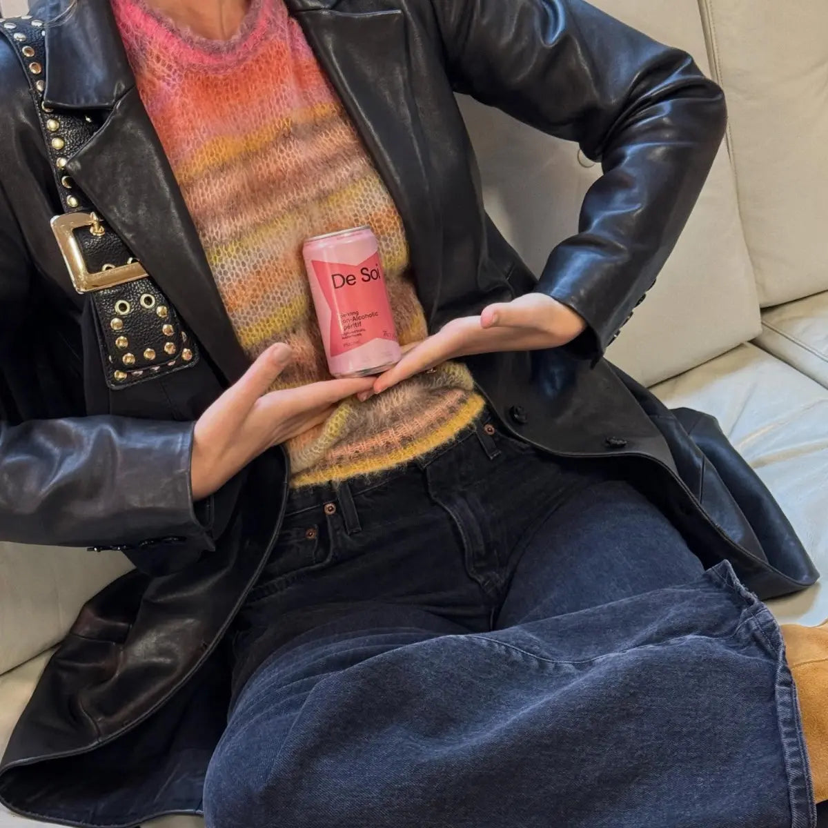 Spring apéritif drinks featuring De Soi Très Rosé held by a stylish person in a colorful sweater and leather jacket