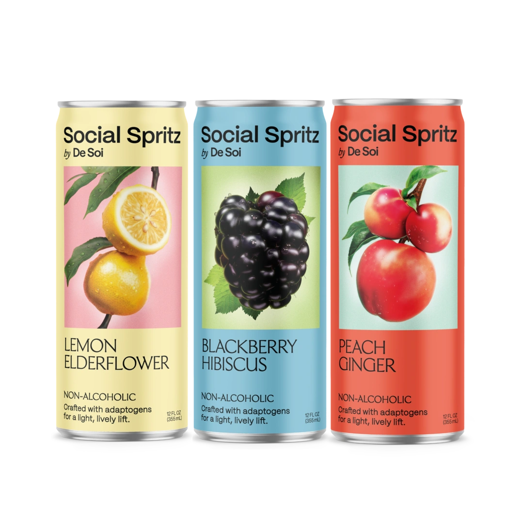 Three cans of Social Spritz by De Soi in Lemon Elderflower, Blackberry Hibiscus, and Peach Ginger, non-alcoholic adaptogen drinks lined up in a row.